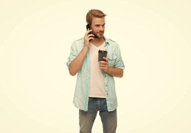 Sabah araması. Genç meşgul bir adam telefonda konuşuyor. Millennial 'daki adam telefonla arıyor. Beyazdan izole edilmiş. Telefonla ve kahveyle arayan adam. Sohbet edelim. Kahve molası. İletişim becerileri.