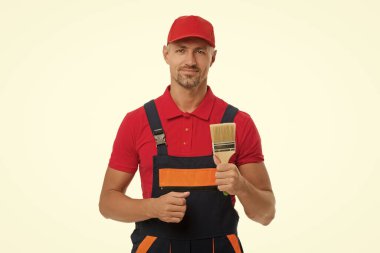 Tadilat işi. Dekoratör boyama yapıyor. Yenileyen adam beyazda izole edildi. Boyacı tadilatı. Ev tadilatı. Boya fırçası tutan erkek ressam. Dekoratör için boya fırçası. Biçim özelleştiriliyor.