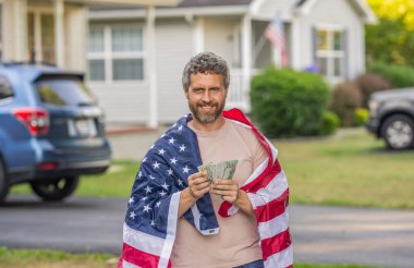 Vergi sistemi. Vatansever adam. Amerikan bayrağı ve dolar parası olan adam. Enflasyon konsepti. Amerikan vergi politikası. İspanyol adam ve Amerikan bayrağı. Amerika 'da vergi ödemek. Katma değer vergisi. Vergi ödemek.