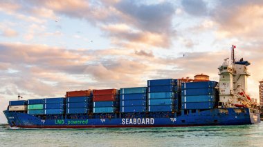 Miami, Florida, ABD - 14 Aralık 2024: Kargo Kıyısı mavi gemi hizmetleri konteynır, hava günbatımı manzaralı. Kargo gemisinde nakliye konteynırı. Kargo gemisi. Miami limanı. Konteyner gemisi.