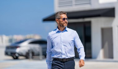 Başarılı bir iş lideri. İş adamının iş başarısı. İş adamı liderliği. Üst düzey yönetici yürüyor. Güneş gözlüklü zengin adam. Dışarıda başarılı bir iş adamı. İşadamı tarzı bir portre..