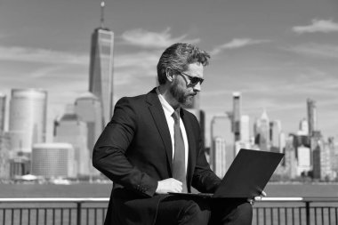 İş adamı dışarıda dizüstü bilgisayarla çalışıyor. Adam iş e-postası ve internette sörf yapıyor. Dijital veri yönetimi. New York 'ta serbest çalışan bir iş adamı. İnternette çalışan bir iş adamı. Mali strateji.