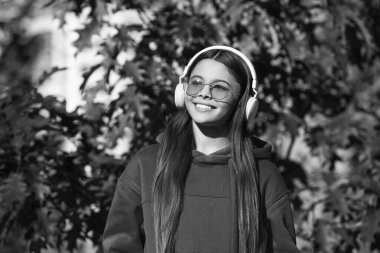 Müzik molası. Sonbahar ormanının tadını çıkar. Kız kulaklıkla müzik dinliyor. Ilık sonbahar. Kulaklıklı kız dışarıda. Sonbahar parkındaki kız. Müzik yaşam tarzı. Melodik melodiler.