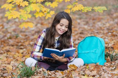 Dışarıda kitap okuyan liseli kız. Genç kız sonbahar parkında kitap okuyor. Eğitim ve bilgi. Bilgi toplama günü. Kendi kendine eğitim. Sonbahar kitabı. Okula dönelim. Okul eğitimi. Şiir okuyorum..