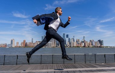 Başarılı iş adamı New York şehrinin siluetinde acele ediyor. Manhattan 'daki iş adamı. Büyük şehirde iş başarısı. İş adamı başarıya koşuyor. İş başarısı. Geç toplantı.