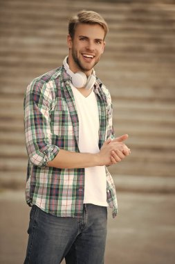 Müzik aşığı yaşam tarzı. Dışarıda müzik kulaklığı takan milenyum adamı. Modern yaşam tarzı. Öğrenci hayatı. Öğrenci adamın kulaklığında müzik var. Milenyum kuşağı sesi dinler. Fonksiyonel moda.