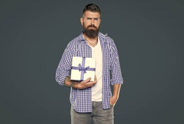 Gri arka planda hediye kutusu olan olgun sakallı adam. Boks günü.