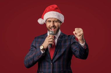 Xmas 'taki başarılı iş adamı sunucusu kırmızıda izole edildi. Xmas iş adamı sunucusu. Noel Baba şapkalı xmas işadamı sunucusu. Mikrofonlu iş adamı sunucusu. Mutlu xmas.