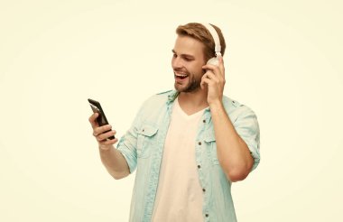 Kulaklıklı adam. Kulaklıklı adam telefonda mp3 çalma listesini seçiyor. Beyazlar içinde izole edilmiş akıllı telefon uygulaması kullanan adam. Telefonla müzik dinlemek. Müzik yaşam tarzı. Ses çalma listesi. Video çağrısı.
