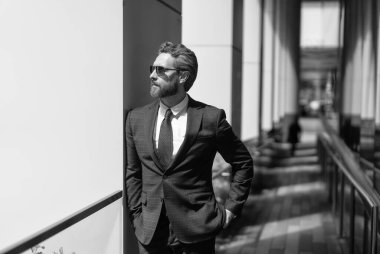 İş adamı kılığındaki başarılı hırslı işadamı modern iş bürosu binasında duruyor..