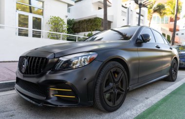 Miami, Florida, ABD - 07 Nisan 2025: Lüks siyah mat Mercedes Benz C W205. Mercedes Benz C W205 dışarıda park halinde. Siyah mat araba, köşe manzaralı. Mercedes Benz C W205 arabası.