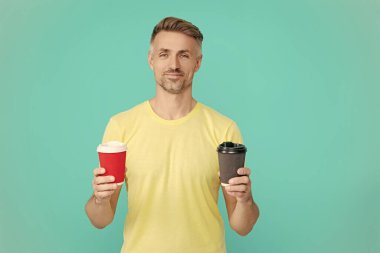 Yaşam tarzı konsepti. Kafeinsiz içiyorum. Çay içen adam. Sıcak bir sabah, rahatla. Kahveci adamla kahve molası. Olgun bir adam mavi üzerine kafeinsiz kahve fincanı seçer. Sabah kahvesi vakti. Sabah titreşimleri.