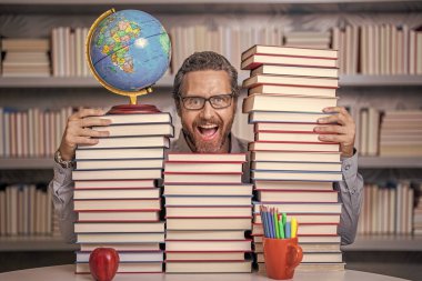 Kitap edebiyatı öğretmeni. Okul kütüphanesinde eğitim. Adam kitap kurdu bilgi topluyor. Öğretmenler ve bilgi günü. Zeki öğretmen. Sınıftaki kitap kurdu adam. Dâhi arayışı.