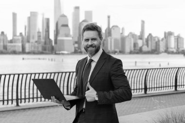 New York 'ta serbest çalışan bir iş adamı. İnternette çalışan bir iş adamı. İş adamı dışarıda bilgisayar ya da dizüstü bilgisayarda çalışmakla meşgul. Adam internet tarayıcısından iş e-postası ve sörf yolluyor. Başparmak yukarı..