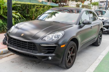 Miami, Florida, ABD - 02 Nisan 2025: siyah mat araba, köşe manzaralı. Porsche Macan 2015 çapraz arabası. Lüks araba Porsche Macan. Porsche Macan 'ın arabası dışarıda park edilmiş..