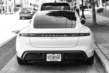 Miami Beach, Florida USA - 9 Haziran 2024 Miami plajında Porsche Taycan beyaz rengi. Ocean 'daki lüks araba porshche' si Miami plajına gidiyor. ön köşe görünümü