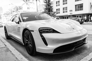Miami Beach, Florida USA - 9 Haziran 2024 Miami plajında Porsche Taycan beyaz rengi. Ocean 'daki lüks araba porshche' si Miami plajına gidiyor. ön köşe görünümü
