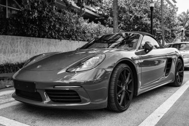 Miami Beach, Florida USA - 9 Haziran 2024: 2018 Porsche 718 Boxter 's orange color at Miami Beach. Ocean 'daki lüks araba porshche' si Miami plajına gidiyor. ön köşe görünümü