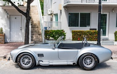 Miami, Florida, ABD - 13 Nisan 2025 AC Kobra spor üstü açık spor spor araba. Dönüştürülebilir araba AC Cobra. Araba AC Cobra dışarıda park edilmiş. Gümüş renkli spor araba, yan görüş..