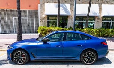 Miami, Florida, ABD - 13 Nisan 2025: BMW i4 M50 2023 elektrikli araba. Lüks elektrikli BMW M50. Araba BMW i4 model M50 elektrikli açık hava parkı. Mavi elektrikli araba, yan görüş..