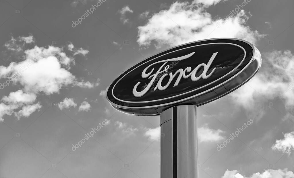 Chicago, USA - August 17, 2024: Ford logo sign against blue cloudy sky. Ford motor company is a oldest car company. Ford sign near dealership