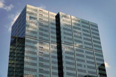 Şehir merkezinde gökdelenli. İş bölgesindeki ofis binası. Gökdelen mimarisi. Camdan yapılmış bir gökdelen. Modern cam bina. Şehir merkezindeki gökdelen. Yükseklik.