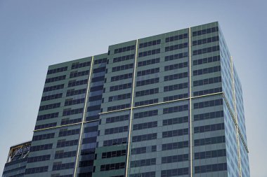 Şehirdeki gökdelen. Şehir merkezinde gökdelenli. İş bölgesindeki ofis binası. Gökdelen mimarisi. Camdan yapılmış bir gökdelen. Modern cam bina. Ticari mimari.