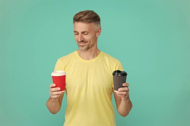 Sabah kahvesi vakti. Yaşam tarzı konsepti. Kafeinsiz içiyorum. Çay içen adam. Sıcak bir sabah, rahatla. Kahveci adamla kahve molası. Olgun bir adam mavi üzerine kafeinsiz kahve fincanı seçer. Cappuccino seçiliyor.