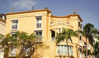 Konut mimarisi. Mimari dış görünüş. Evin dış kısmı parçalanmış. Modern apartman binası. Balkonları ve palmiye ağaçları olan bir apartman. Binanın düşük açılı görüntüsü. Güneşli bir gün.