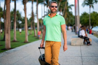 Yaz turu. Gezgin yaz tatilinin tadını çıkar. İspanyol turist caddede yürüyor. Bavullu turist. Erkek gezgin. Yaz tatilindeki turist. Yaz gezisi için seyahat valizleri. Seyahat yaşam tarzı.