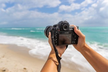 Yaz tatili. Seyahat ve fotoğrafçılık. Fotoğrafçı kamerayla fotoğraf çekiyor. Yaz plajında kameralı bir gezgin. Seyahat fotoğrafçılığı. Yazın seyahat. Deniz sahilindeki fotoğraf makinesi..