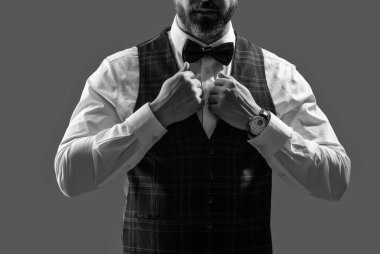 Zarif siyah takım elbiseli şık bir adam. Smokinli bir beyefendi. Resmi etkinlikteki iş adamı. Damadın smokin tarzı var. Centilmen smokini. Smokin, kesilmiş. Papyonlu adam gride izole edilmiş. Smokin Bakımı.