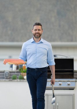 Arka bahçede balık pişiriyorum. Orta yaşlı İspanyol adam ızgara ton balığı ızgarası. Barbekü ve ızgara. Kızartma ve ızgara yemek. Şef BBQ balığı yapar. Adam mutfakta ton balığı pişiriyor. Lüks yemekler..