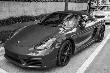 Miami Beach, Florida USA - 9 Haziran 2024: 2018 Porsche 718 Boxter 's orange color at Miami Beach. Ocean 'daki lüks araba porshche' si Miami plajına gidiyor. ön köşe görünümü