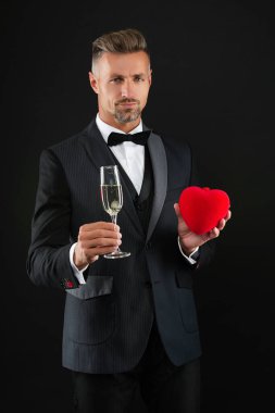 Resmi etkinlikte smokin giyen adam. Şampanyayla kutlayın. Kutlama ve tezahürat. Smokinli adam. Şık smokinli adam siyah üzerine izole edilmiş şampanya bardağı tutuyor. Nişanı kutluyoruz. Şerefe..