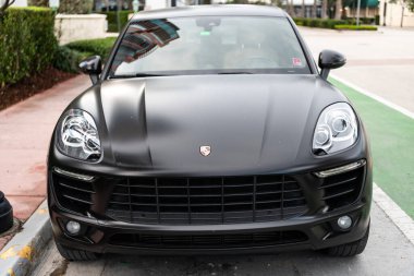 Miami, Florida, ABD - 02 Nisan 2025: siyah mat araba, ön manzara. Porsche Macan 2015 çapraz arabası. Lüks araba Porsche Macan. Porsche Macan 'ın arabası dışarıda park edilmiş..