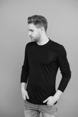 Beyazlı genç bir adam gri yolda izole edilmiş. Kendine güvenen adam portresi. Erkeklerin cilt bakımı. Erkek derisi. Adamın şık bir saç kesimi var. Moda saç stili olan bir adam. Sıradan erkek tarzı. Çarpıcı derecede yakışıklı..