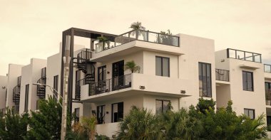 Balkonları ve palmiye ağaçları olan bir apartman. Bina manzarası. Konut mimarisi. Mimari dış görünüş. Evin dış kısmı parçalanmış. Modern apartman binası. Yaz tatili.