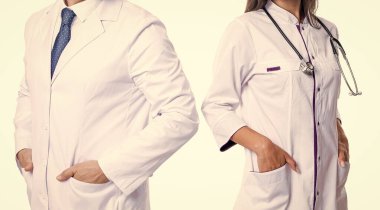 Steteskobu olan doktor beyaza izole edilmiş. Paltolu profesyonel doktor ve tıp kadını. İlaç ve sağlık sigortası. Hastanedeki doktor. Tıp alanında iki doktor. Tamamlayıcı uygulayıcı.