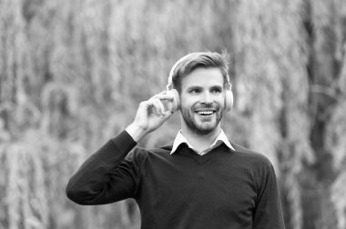 Mutlu genç yakışıklı dışarıda kulaklıkla müzik dinliyor..