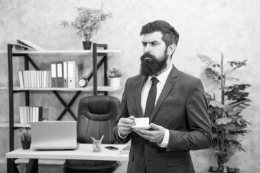 serious mature entrepreneur in jacket having coffee break at office, business.