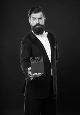 man in tuxedo bow tie formalwear on black background with business reward box. occasion greeting.