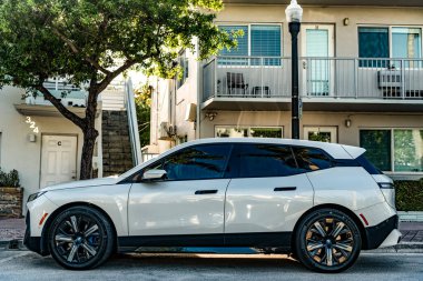 Miami, Florida, ABD - 05 Nisan 2025: BMW IX elektrikli SUV açık havada park edilmiş. Beyaz renkli araba, yan görüş. 2025 BMW xDrive50 lüks elektrikli arazi aracı. Elektrikli geçiş aracı BMW IX xDrive50.