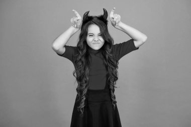 Mutlu Cadılar Bayramı. Cadılar Bayramı partisi için turuncu giysili dişi şeytan hazır. Şeker mi şaka mı? Tüm Cadılar Bayramı parti kutlaması. Cadılar Bayramı partisi eğlencesi. Dişi şeytan Cadılar Bayramı partisinde eğleniyor. Kırmızı şeytan boynuzları.