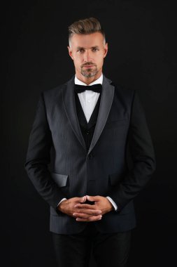 Zengin ısmarlama smokinli adam. Siyah takım elbiseli smokinli adam izole edilmiş. Resmi erkek giyim sektöründe başarılı bir adam. Erkek giyim tarzı. Şık smokin papyonu. Resmi etkinlikte zengin iş adamı.