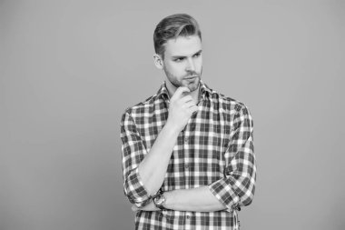 Gündelik giyinen milenyum adamı. Yakışıklı genç adam. Sıradan gömlekli bir adamın portresi. Gri üzerinde kollarını çapraz tutuyor. Tıraşsız erkek derisi. Erkek güzelliği ve saç stili. Erkek saç kesimi.