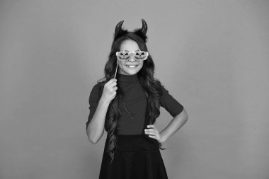 Dişi şeytanın Cadılar Bayramı partisinde aksesuarı var. Mutlu Cadılar Bayramı. Cadılar Bayramı partisi için turuncu giysili dişi şeytan hazır. Şeker mi şaka mı? Tüm Cadılar Bayramı parti kutlaması. Komik aksesuarları kutlar.