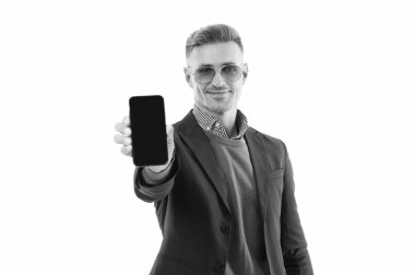 Ürünü sunuyorum. İş uygulamasının reklamı. Olgun iş adamı telefon ekranını sunuyor. İş adamı, telefonun beyazda izole olduğunu gösteriyor. Adam yeni iş telefonu uygulamasını gösteriyor. Seçici odak.