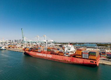 Miami, Florida, ABD - 20 Mart 2025: Kargo Hamburg Sud konteynır hizmetleri Miami 'de, hava manzaralı. Kargo gemisinde nakliye konteynırı. Kargo gemisi. Miami limanı. Konteyner gemisi.