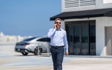 Müzakere çevrimiçi. İş adamı dışarıda telefonla konuşuyor. Telefon kullanan bir iş adamı. İş görüşmesi. Erkek telefon konuşması. Telefonu olan olgun bir adam. İş iletişimi. İş modeli.